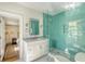 Bright bathroom features a glass shower with green tile, a vanity with marble top, and white cabinets at 304 Bank St, Mount Pleasant, SC 29464