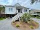 Charming two-story home with a palm tree in the yard, complemented by gray gravel and white stairs at 3510 Myrtle St, Edisto Island, SC 29438