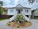 Beautiful two-story home with a palm tree in the yard, complemented by gray gravel and white stairs at 3510 Myrtle St, Edisto Island, SC 29438