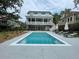 Bright in-ground pool with surrounding lounge chairs, umbrellas, and a two-story home in the background at 3510 Myrtle St, Edisto Island, SC 29438