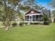 Well-maintained red home features a screened-in porch, lush lawn, and vibrant landscaping at 402 N Hickory Street St, Summerville, SC 29483