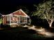 Nighttime view of a red home with landscape lighting, a screened porch, and a cozy, welcoming vibe at 402 N Hickory Street St, Summerville, SC 29483