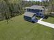 Aerial view of a blue two-story home with a detached garage, surrounded by a lush green lawn and mature trees at 4235 Royal Harbor Rd, Hollywood, SC 29449