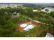 An aerial view showcasing a modern white home with a private pool and surrounding mature trees and a golf course at 4310 Stonehouse Cir, Awendaw, SC 29429