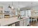 Bright kitchen island with a stainless steel sink, quartz countertop, and views of living and dining areas at 5560 Alpine Dr, Summerville, SC 29483