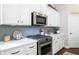 Well-lit kitchen featuring stainless steel appliances, grey backsplash, and white cabinets at 5560 Alpine Dr, Summerville, SC 29483