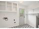 Bright laundry room featuring black-and-white patterned floor, ample shelving, and access to the backyard at 5573 Betty Ct, North Charleston, SC 29418
