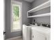 Bright laundry room featuring modern washer and dryer with shelving at 8499 Falling Leaf Ln, North Charleston, SC 29420
