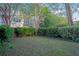 Private backyard featuring a lush lawn, mature trees, and neat hedges with multi story condos in the background at 9028 Parlor Dr, Ladson, SC 29456