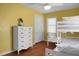 This bedroom showcases a bunk bed, a white dresser, and a window allowing natural light to illuminate the cheerful yellow space at 1113 Smithfield Pl, Hanahan, SC 29410