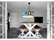 Bright dining room featuring a farm-style table, benches, beach-themed TV, modern lighting, and gray laminate flooring at 1113 Smithfield Pl, Hanahan, SC 29410