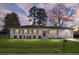 Charming painted-brick home with a well-manicured lawn and classic wood shutters at sunset at 1113 Smithfield Pl, Hanahan, SC 29410