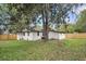View of the home's rear with a white brick exterior, wooden fence, and a well-maintained grassy yard at 1249 Sumner Ave, North Charleston, SC 29406