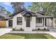 Eye-level view of white brick home with black trim, updated garage door, manicured lawn and front porch at 1249 Sumner Ave, North Charleston, SC 29406