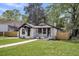 Landscaped home with white painted brick, dark trim, attached garage, front porch, and manicured lawn at 1249 Sumner Ave, North Charleston, SC 29406