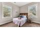 Cozy bedroom with two windows and neutral walls filled with a wooden frame bed and side table at 135 Marshside Dr, Summerville, SC 29485