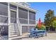 Outdoor patio features a table with chairs, steps up to the screened porch, and lush landscaping at 1555 Willtown St, Daniel Island, SC 29492
