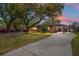 Charming brick home with mature trees, covered carport, and well-manicured lawn under a colorful sunset sky at 1673 Mcclain St, Charleston, SC 29407