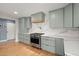 Modern kitchen with sleek light green cabinets, stainless steel appliances, and hardwood flooring at 1673 Mcclain St, Charleston, SC 29407