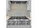 Close up of a stainless steel Monogram gas range with a modern backsplash and hood at 1857 W Canning Dr, Mount Pleasant, SC 29466