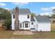White two-story home featuring a brick chimney and a concrete patio, surrounded by green trees and a blue sky at 201 Driver Ave, Summerville, SC 29483