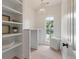Bright laundry room features white shelving, a modern chandelier, and a large window for natural light at 2226 Red Fern Lane, Mount Pleasant, SC 29466