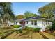 Charming single-story white brick home featuring a well-manicured lawn, mature trees, and lovely landscaping at 3 Lauden Blvd, Isle of Palms, SC 29451