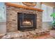 A red brick fireplace with wood burning behind a black protective screen at 306 Teakwood Dr, Walterboro, SC 29488