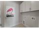 Bright laundry room with white cabinets and a flamingo art piece on the wall adds a whimsical touch at 4155 Jean Laffite Rd, Hollywood, SC 29449