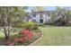 Beautiful two-story home framed by mature trees, a vibrant flowerbed, and a brick-lined garden at 506 Fairington Dr, Summerville, SC 29485