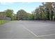A well-maintained tennis court surrounded by lush green trees and featuring a bench between the nets at 506 Fairington Dr, Summerville, SC 29485