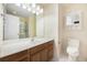 Bathroom with white countertops, wooden cabinets, large mirror, vanity lighting, toilet, and a tiled shower at 8739 Grassy Oak Trl, North Charleston, SC 29420