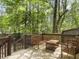 A wooden deck featuring a bench, chairs, and table, surrounded by a lush forest and nature at 8810 Gilston Ln, North Charleston, SC 29420