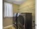 Laundry room featuring modern front-loading washer and dryer set with shelving above, and a window at 8810 Gilston Ln, North Charleston, SC 29420