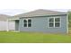 This home's backyard features two large windows, blue siding, manicured lawn, and a covered porch at 1052 Forrest Creek Dr, Summerville, SC 29483