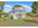 Raised beach house with white accents, garage parking, and greenery highlighting its inviting and functional design at 1224 Midvale Ave, Charleston, SC 29412