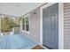 View of the blue-floored porch with a gray front door, side lights, and a view of the wooded area at 1224 Midvale Ave, Charleston, SC 29412
