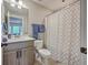 Well-lit bathroom with a single sink vanity, toilet, tiled floor, and shower with a patterned curtain at 1816 Orangeburg St, North Charleston, SC 29405