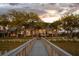 Scenic backyard view from the dock, showcasing the home's lights, expansive lawn, and mature trees at sunset at 1954 Sandy Point Ln, Mount Pleasant, SC 29466