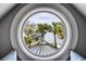 Scenic view of dock and palm trees framed by a round window from the cozy window seat at 1954 Sandy Point Ln, Mount Pleasant, SC 29466