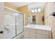 Well-lit bathroom with floral wallpaper, a white vanity, and a shower-tub with glass doors at 21 Rutledge Ave, Charleston, SC 29401
