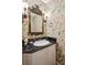 Charming powder room featuring floral wallpaper, a black marble countertop, and a decorative mirror at 21 Rutledge Ave, Charleston, SC 29401