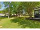 View of the backyard shows a large area of grass, along with mature trees and screen porch at 407 Burton Ave, Summerville, SC 29485