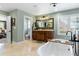 Bright bathroom featuring a soaking tub, travertine tile, and dark wood vanity at 4217 Sawgrass Dr, Charleston, SC 29420