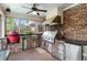 Well-equipped outdoor kitchen on a screened porch with brick accents and modern appliances at 4217 Sawgrass Dr, Charleston, SC 29420