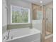 Bright bathroom featuring a soaking tub with a large window and a glass-enclosed shower at 86 Red Bluff St, Summerville, SC 29483