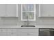 Close-up of a kitchen sink area featuring white countertops, subway tile backsplash, and stainless steel fixtures at 86 Red Bluff St, Summerville, SC 29483
