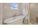 Bright bathroom with soaking tub, marble tile, window, and walk-in shower with pebble floor at 9 Marsh Island Ln, Isle of Palms, SC 29451