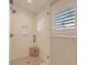 Bright white shower with glass doors, built-in shelving, and modern fixtures, next to a sunny window at 9 Marsh Island Ln, Isle of Palms, SC 29451