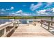 Exterior image of a private wooden dock with a ladder and boats on the water with a scenic marsh view under a sunny sky at 100 Tidewater Way, Charleston, SC 29492